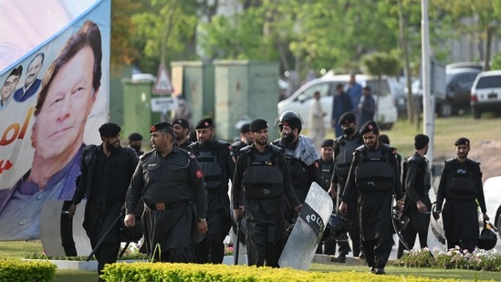 Security personnel walk past a banner featuring an image of Pakistan's Prime Minister Imran Khan near Parliament in Islamabad. (AFP)