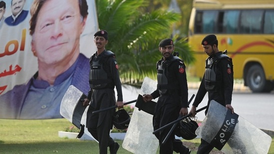 Security personnel walk past a banner featuring an image of Pakistan's Prime Minister Imran Khan near Parliament House building in Islamabad. (AFP)