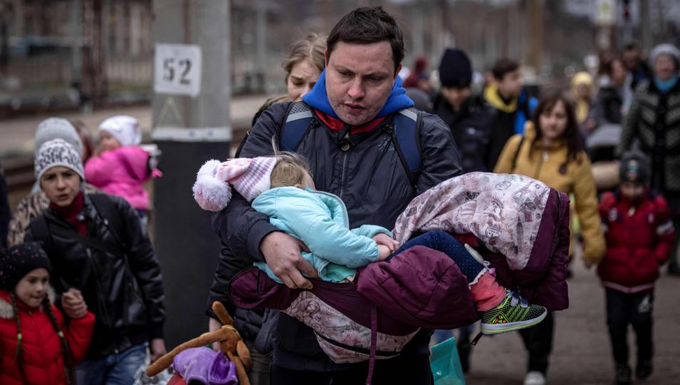 A man carries a little girl as he arrives with other families to board a train at Kramatorsk central station as they flee the eastern city of Kramatorsk, in the Donbass region of Ukraine, on Monday. (AFP)