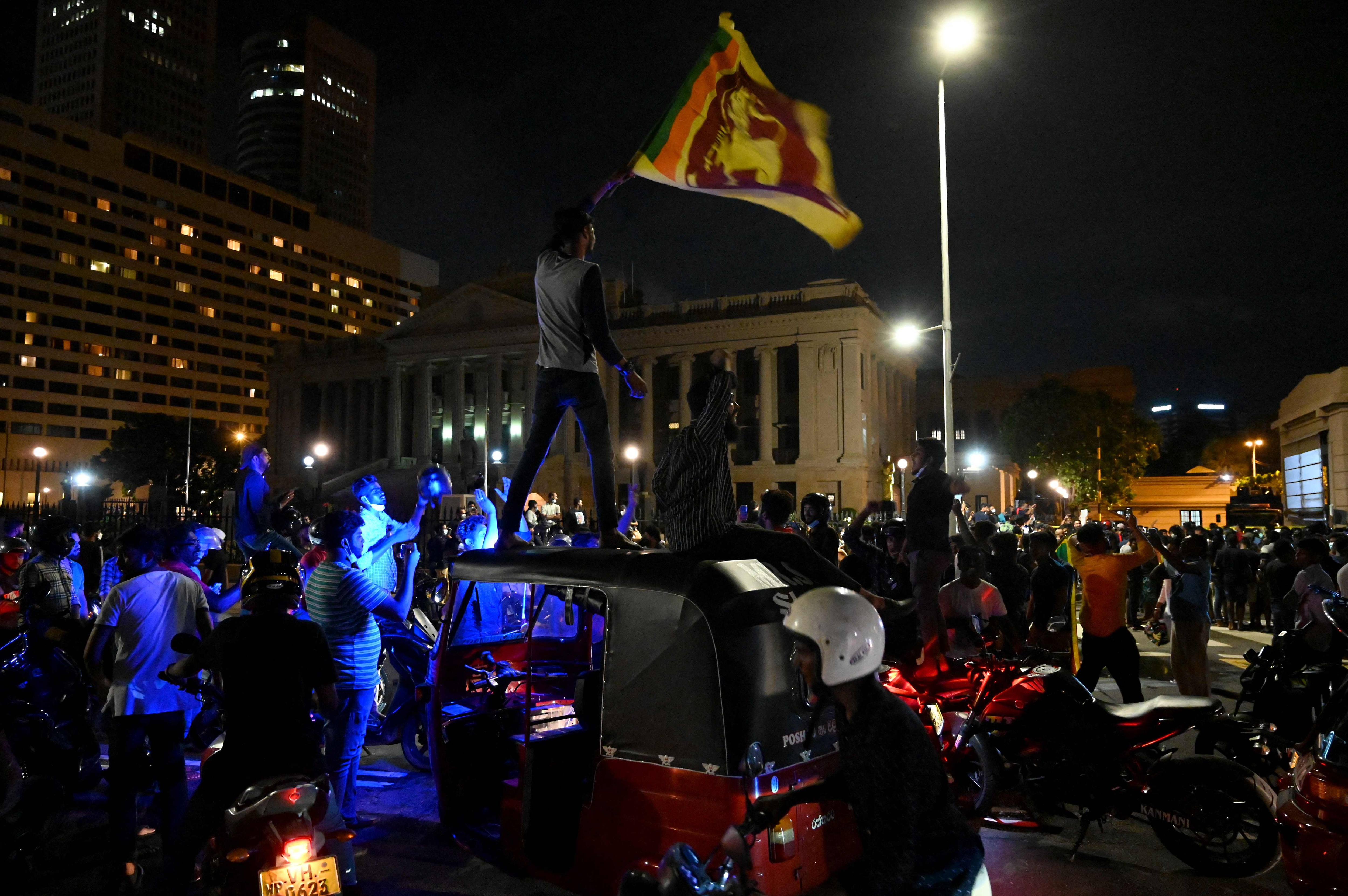 Protestors hold Sri Lanka's flag during a demonstration against the surge in prices and shortage of fuel and other essential commodities at the entrance of the president's office in Colombo on April 4, 2022. (AFP) Protestors hold Sri Lanka's flag during a demonstration against the surge in prices and shortage of fuel and other essential commodities at the entrance of the president's office in Colombo on April 4, 2022. (AFP)