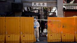 A worker in a protective suit stands behind barriers sealing off a residential area under lockdown, following the coronavirus disease (COVID-19) outbreak in Shanghai, China, on March 29. (REUTERS)