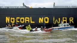 Activists from Greenpeace paint a slogan at the coal freighter "Grand T", which is loaded with Russian coal, on its way to the port in Hamburg, in Wedel, Germany. (REUTERS/Fabian Bimmer)