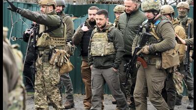 Ukrainian President Volodymyr Zelensky (centre) examines the site of a recent battle in Bucha close to Kyiv, Ukraine, on Monday. (AP)