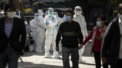 Workers in personal protective equipment (PPE) keep watch as residents queue for a Covid-19 test in a neighborhood placed under lockdown in Shanghai, China, on Monday, April 4, 2022. Photographer: Qilai Shen/Bloomberg (Bloomberg)