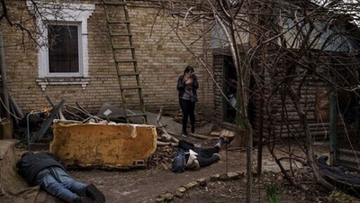 Ira Gavriluk holds her cat as she walks among the bodies of her husband, brother, and another man, who were killed outside her home in Bucha, on the outskirts of Kyiv, Ukraine. (AP)