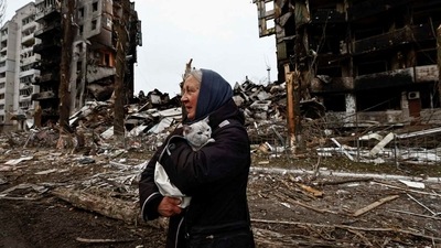 A woman carries her cat as she walks past buildings destroyed by Russian shelling in Ukraine's Borodyanka. (REUTERS)