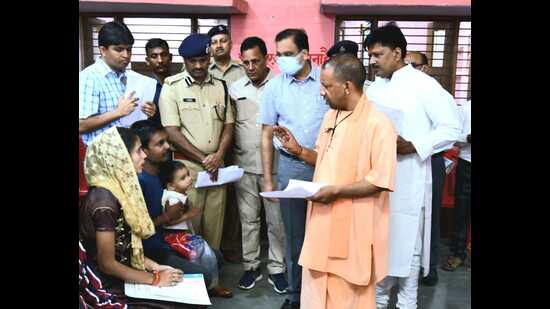 Chief minister Yogi Adityanath talking to parents of three-year-old Shreyansh during the ‘Janta Darshan’ on Gorakhnath temple premises, in Gorakhpur on Tuesday. (HT PHOTO)