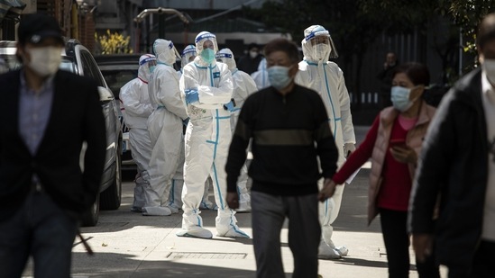 Workers in personal protective equipment (PPE) keep watch as residents queue for a Covid-19 test in a neighborhood placed under lockdown in Shanghai, China, on Monday, April 4, 2022. Photographer: Qilai Shen/Bloomberg(Bloomberg)