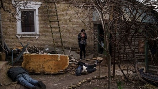 Ira Gavriluk holds her cat as she walks among the bodies of her husband, brother, and another man, who were killed outside her home in Bucha, on the outskirts of Kyiv, Ukraine.(AP)