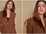 Yami Gautam once again reached the sets of The Kapil Sharma Show to promote her upcoming film Dasvi. For the episode, the actor donned a stylish long trench-coat inspired brown jacket with multiple buttons.(Instagram/@yamigautam)