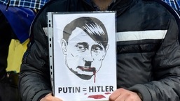 A man holds a placard depicting Russian President Vladimir Putin as Adolf Hitler during a protest against the Russian invasion of Ukraine in Montenegro,