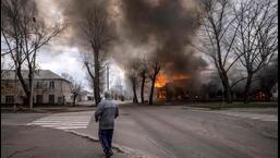 A man walks on a pavement as a house is burning following a shelling Severodonetsk, Donbass region, on Wednesday, as Ukraine tells residents in the country's east to evacuate "now" or "risk death" ahead of a feared Russian onslaught on the Donbas region, which Moscow has declared its top prize. (AFP)
