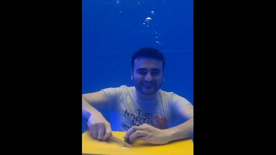 The image, taken from the Instagram video, shows the chef cutting a cucumber while underwater. (Instagram/@cznburak)