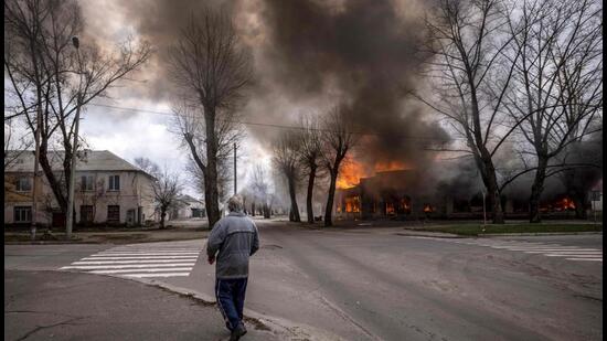 A man walks on a pavement as a house is burning following a shelling Severodonetsk, Donbass region, on Wednesday, as Ukraine tells residents in the country's east to evacuate "now" or "risk death" ahead of a feared Russian onslaught on the Donbas region, which Moscow has declared its top prize. (AFP)