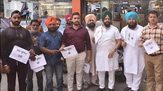 BJP leader Gurdeep Gosha with other traders holding hand fans to protest against AAP, the state government, at Clock tower in Ludhiana on April 06, 2022. (Gurpreet Singh/HT)