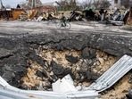 A local resident rides a bicycle past a bomb crater, as Russia's attack on Ukraine continues, in the village of Demydiv, outside Kyiv, Ukraine.