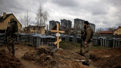 Ukrainian soldiers stand next to the grave of a civilian, who according to residents was killed by Russian soldiers, amid Russia's invasion of Ukraine, in Bucha, Kyiv region, Ukraine. (REUTERS)
