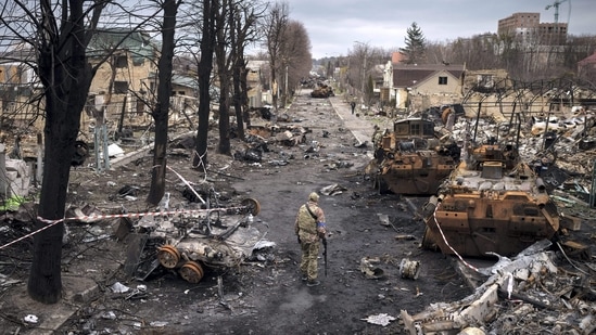 A Ukrainian serviceman walks amid destroyed Russian tanks in Bucha, on the outskirts of Kyiv, Ukraine.(AP)