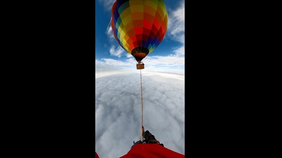 The image, taken from the Instagram video shared by Guinness World Records, shows the man walking on a rope tied between two hot air balloons.(Instagram/@guinnessworldrecords)