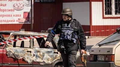 A Ukrainian police walks by calcinated cars outside a train station in Kramatorsk, eastern Ukraine, that was being used for civilian evacuations, after it was hit by a rocket attack killing at least 35 people, on April 8, 2022. (Photo by FADEL SENNA / AFP) (AFP)