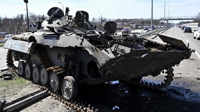 Cars drive past burnt Russian armored personnel carrier (APC) on a road west of Kyiv, (AFP)