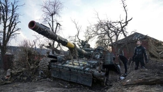 Men stand next to a destroyed tank in Chernihiv, Ukraine, Thursday, April 7, 2022.&nbsp;(AP)