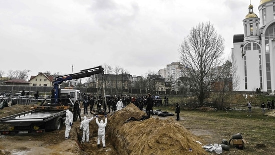 Ukrainian investigators exhume bodies from a mass grave in the gardens of the St Andrew church in the town of Bucha, northwest of Kyiv, on April 8, 2022, during Russia's military invasion launched on Ukraine.&nbsp;(AFP)