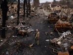 A Ukrainian serviceman stands amid destroyed Russian tanks in Bucha, on the outskirts of Kyiv, Ukraine