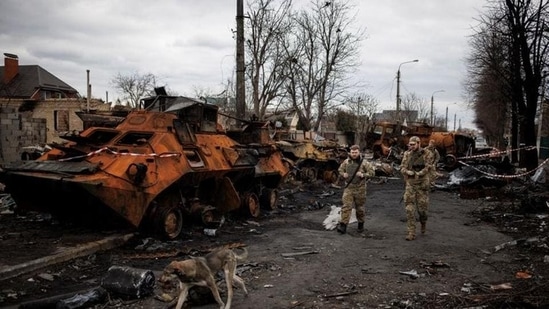 Ukrainian soldiers walk past a destroyed Russian tank amid Russia's invasion of Ukraine, in Bucha in Kyiv region in Ukraine. (REUTERS PHOTO.)