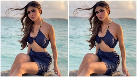 The first photo shows Mouni in a dark blue sleeveless bralette featuring a halter neckline, gathered details and an inverted hem. She teamed it with a matching mini skirt with similar ruched up elements. She wore the ensemble with layered gold chunky chains, open windblown tresses, smoky eye shadow, kohled eyes, and sunkissed skin.(Instagram/@imouniroy)