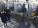 People wearing protective face masks walk past bulletin boards with official campaign posters of French presidential election candidates near a polling station, during the first round of the 2022 French presidential election, in Paris, France.&nbsp;