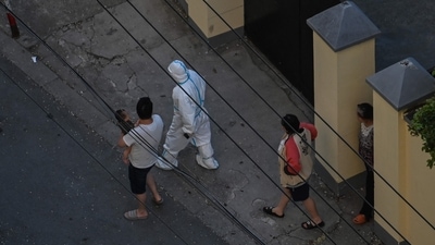 A worker wearing personal protective equipment (PPE) walks with residents during a COVID-19 lockdown in the Jing'an district in Shanghai. (AFP)