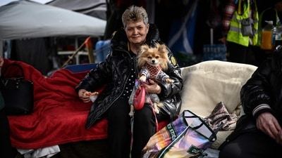 An Ukrainian refugee (C) holds her pet dog as she sits at an NGO tent at the Ukrainian-Polish border on her way out of Ukraine, in Medyka, eastern Poland on Friday. Europe has not seen such a flood of refugees since World War II. (Photo by Christophe ARCHAMBAULT / AFP) An Ukrainian refugee (C) holds her pet dog as she sits at an NGO tent at the Ukrainian-Polish border on her way out of Ukraine, in Medyka, eastern Poland on Friday. Europe has not seen such a flood of refugees since World War II. (Photo by Christophe ARCHAMBAULT / AFP)