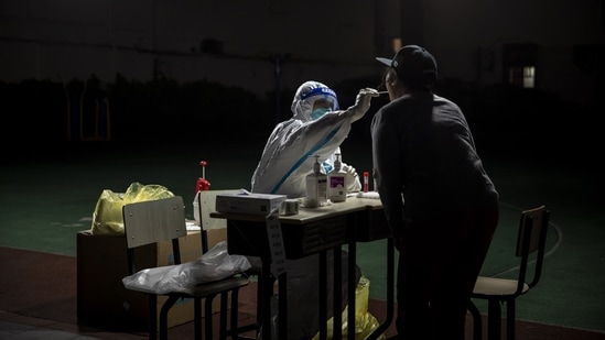 A worker in personal protective equipment (PPE) collects swab sample from a person for a Covid-19 test.(Bloomberg)