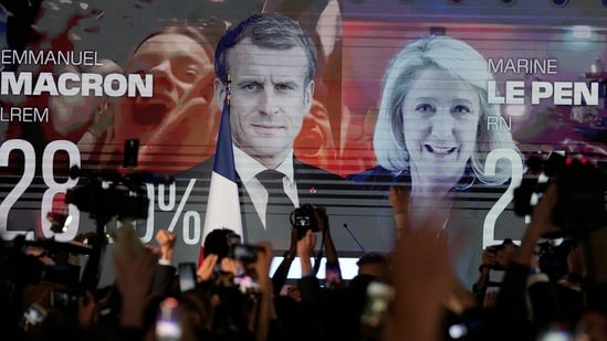 A screen shows French President Emmanuel Macron and centrist candidate for reelection and far-right candidate Marine Le Pen at her election day headquarters, in Paris.(AP)