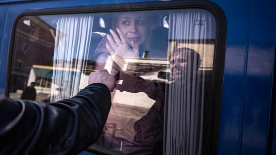  A woman waves to say good bye to her husband as she leaves on a bus, a day after a rocket attack at a train station in Kramatorsk, on Saturday. Ninety percent of those who have fled Ukraine are women and children, as the Ukrainian authorities do not allow men of military age to leave, AFP reports.(Photo by FADEL SENNA / AFP)