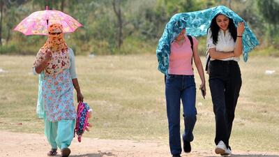 Women try to take cover from the scorching heat at Panjab University in Chandigarh on Monday. (Ravi Kumar/HT)