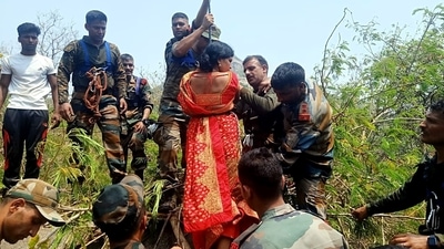Paramilitary personnel rescue a woman during an operation carried out by Indo-Tibetan Border Police (ITBP) and National Disaster Response Force (NDRF) personnel, where the ropeway trolley accident took place, near Trikut, in Deoghar on Monday. (ANI Photo)
