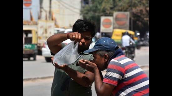 A man drinking water from a plastic bag on a hot summer day in Gurugram on Saturday. (HT PHOTO)