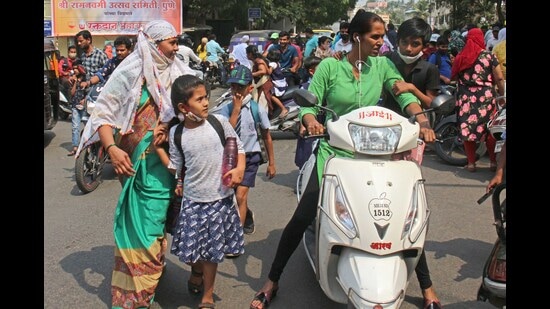 Parents are seen picking up their children from school in the sweltering heat on Monday. (Ravindra Joshi/HT PHOTO)