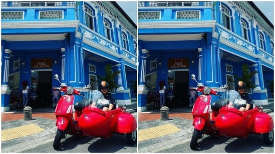 Here's a picture of Gul posing in the red motorcycle with sidecar against a bright blue building in Singapore.(Instagram/@gulpanag)