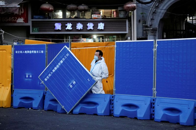 A worker in a protective suit keeps watch next to barricades set around a sealed-off area, during a lockdown to curb the spread of Covid-19 in Shanghai on April 11, 2022.&nbsp; (Reuters Photo)