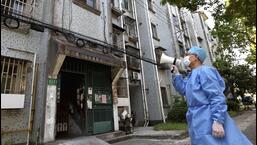 A volunteer uses a megaphone to talk to residents at an apartment building in Shanghai, China, on Tuesday. (AP)