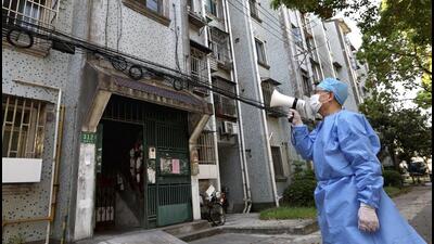 A volunteer uses a megaphone to talk to residents at an apartment building in Shanghai, China, on Tuesday. (AP) A volunteer uses a megaphone to talk to residents at an apartment building in Shanghai, China, on Tuesday. (AP)