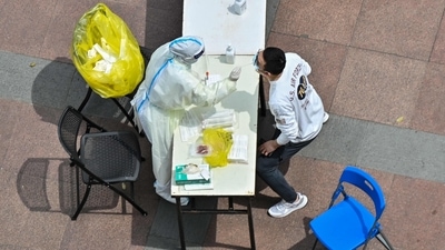 A health worker wearing personal protective equipment (PPE) conducts a swab test for the Covid-19 coronavirus in a compound during a Covid-19 lockdown in the Jing'an district in Shanghai. (AFP)