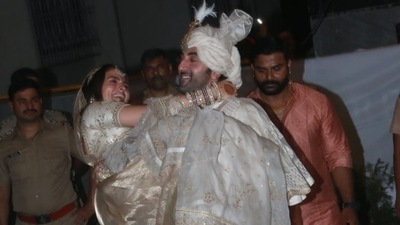 Ranbir Kapoor lifts Alia Bhatt in his arms outside his house after posing for pictures at their wedding.