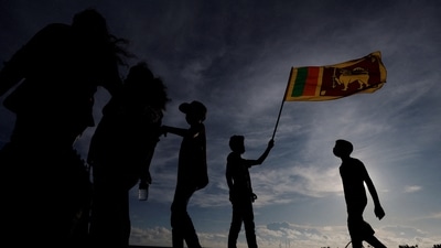 A demonstrator holds a Sri Lankan national flag during the protest against Sri Lanka President Gotabaya Rajapaksa in front of the Presidential secretariat, amid the country's economic crisis in Colombo, Sri Lanka. (REUTERS)