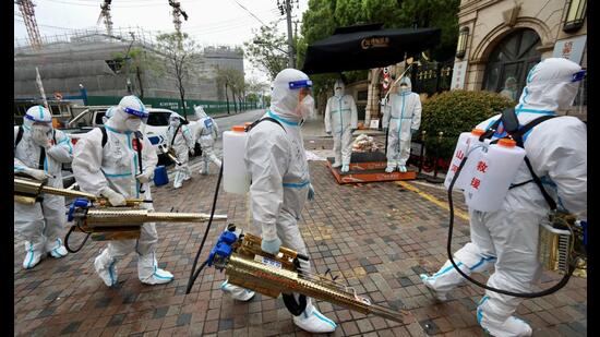 Volunteers in protective suits prepare to disinfect a residential compound in Huangpu district, to curb the spread of Covid-19, in Shanghai, China, on Thursday. (REUTERS)