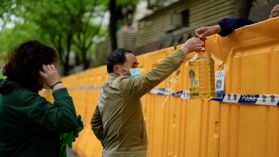 FILE PHOTO: People pass edible oil over the barriers at a street market under lockdown amid the coronavirus disease (COVID-19) pandemic, in Shanghai, China.&nbsp;(REUTERS)