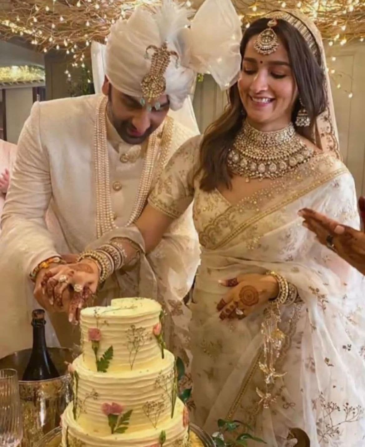 Ranbir Kapoor and Alia Bhatt cutting their wedding cake together.